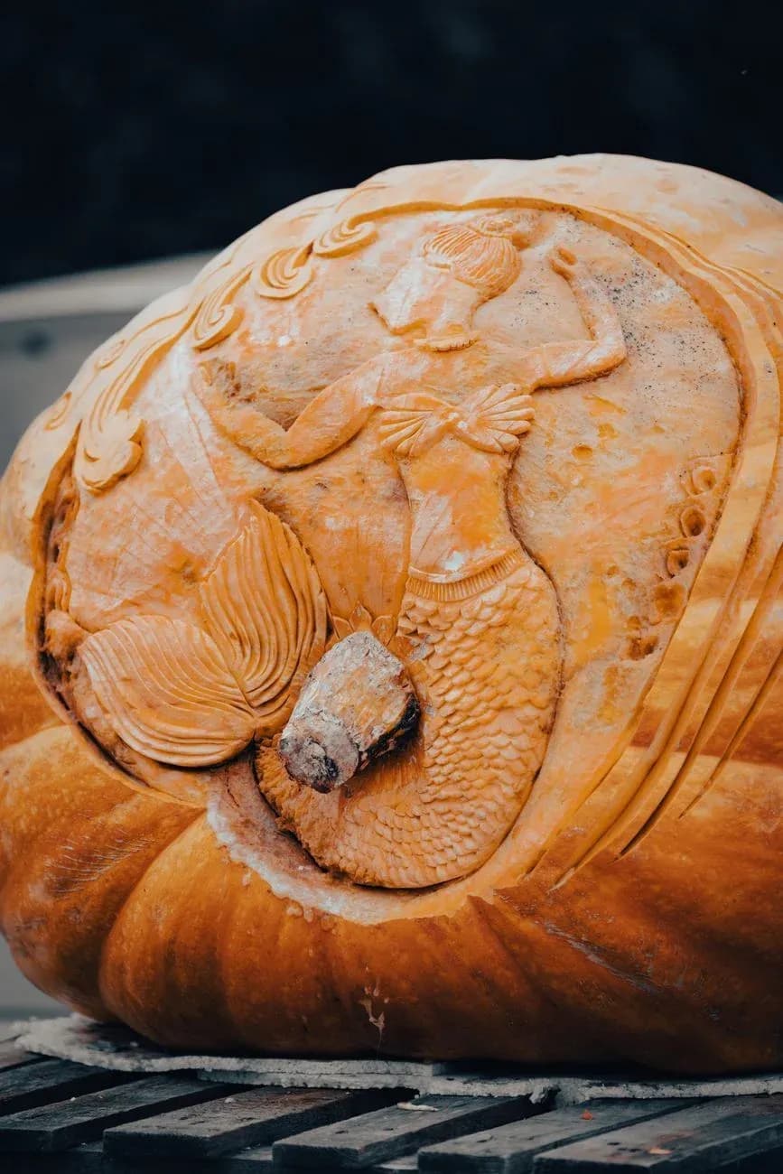 A giant pumpkin carved in deep relief with the figure of a mermaid.