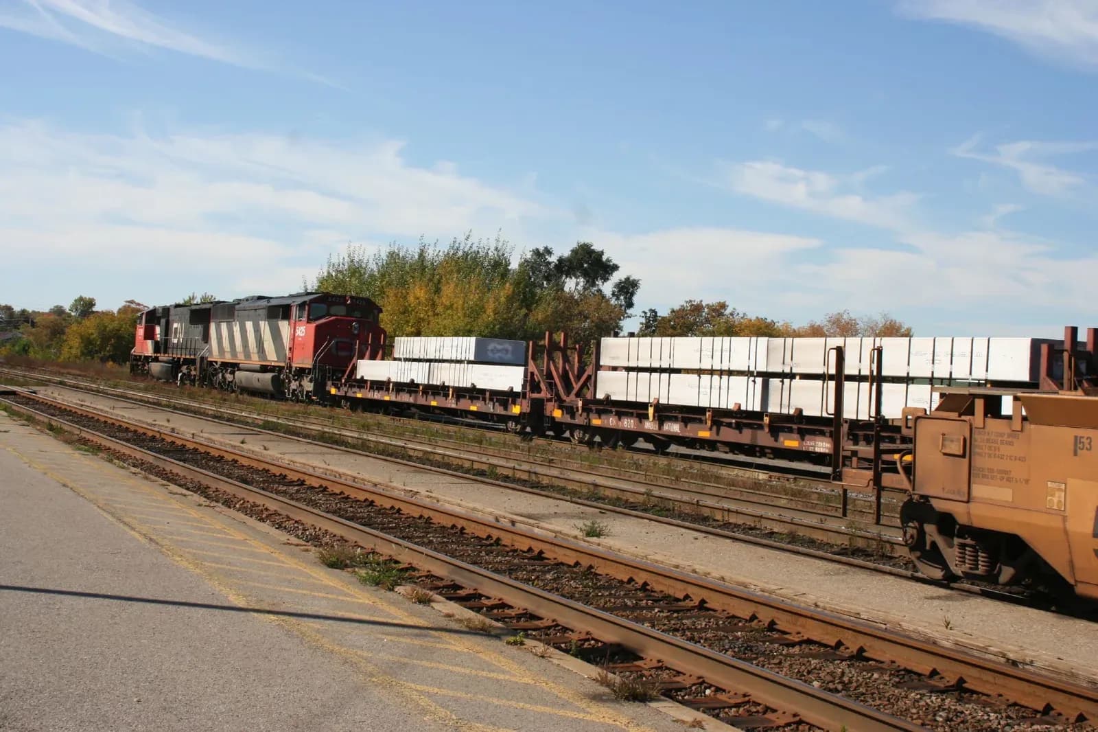 Bundles of aluminum stacked on rail freight cars in a yard