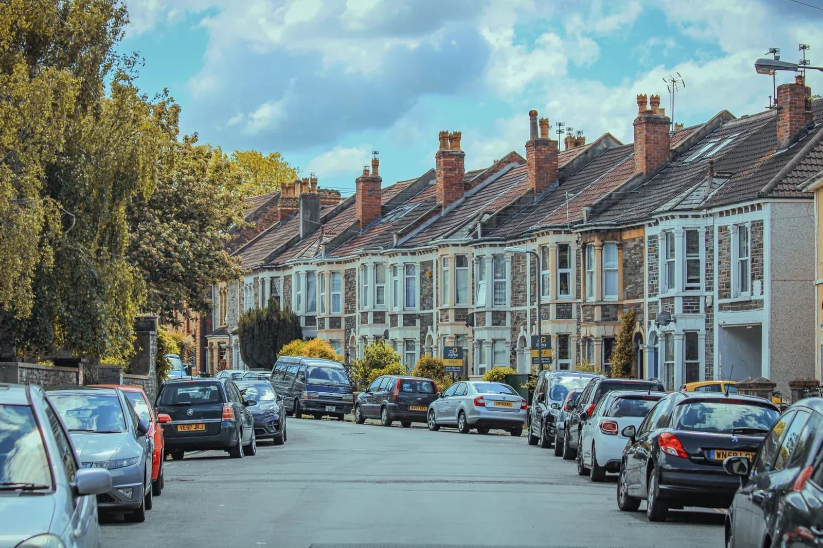 A row of terraced houses with cars parked along a residential street in Bristol.