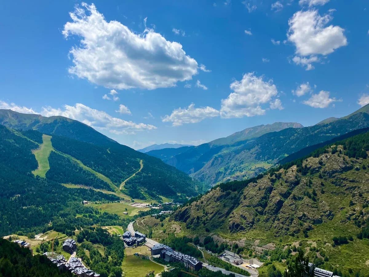 A small village in a green mountain valley with ski runs cut into the slopes above.