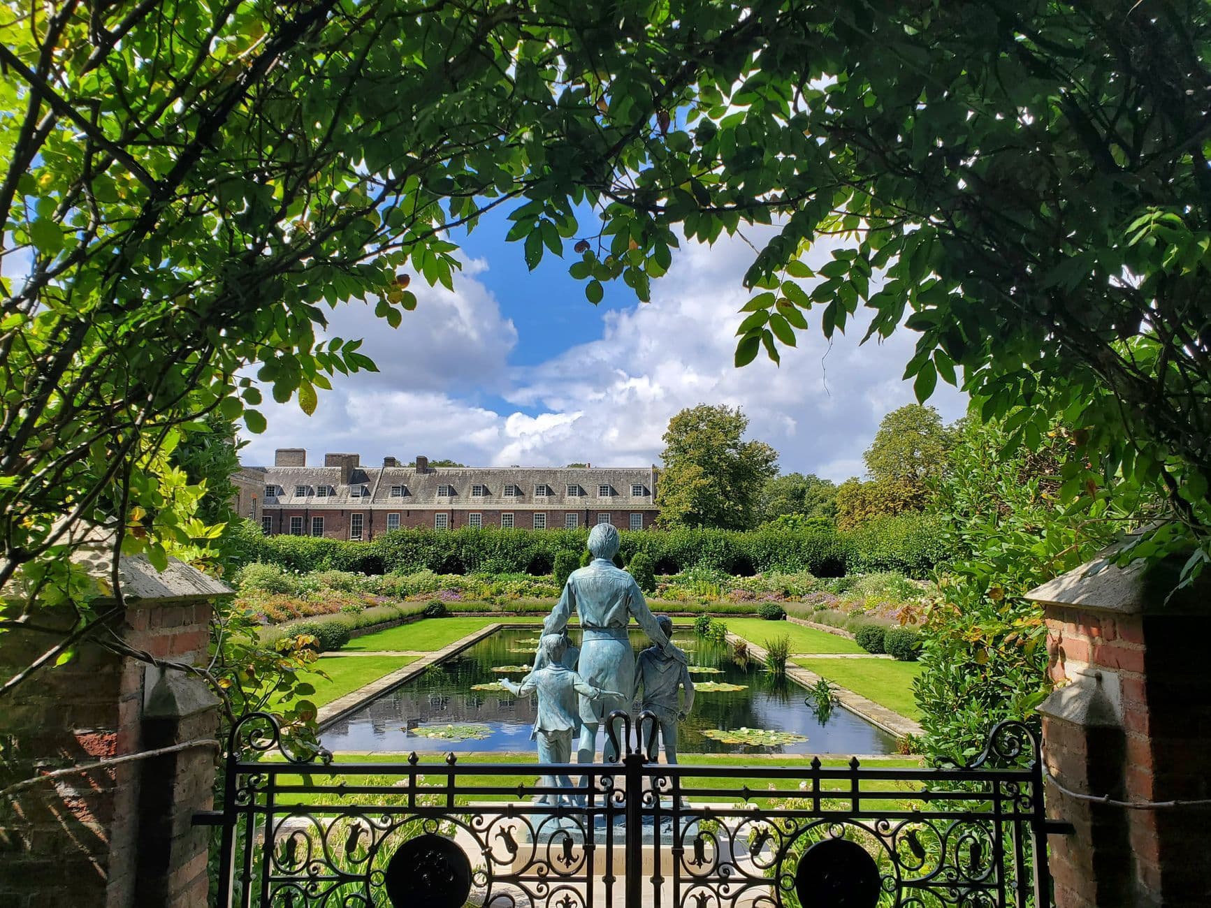 A peaceful view of the Sunken Garden with a sculpture at Kensington Palace in London.