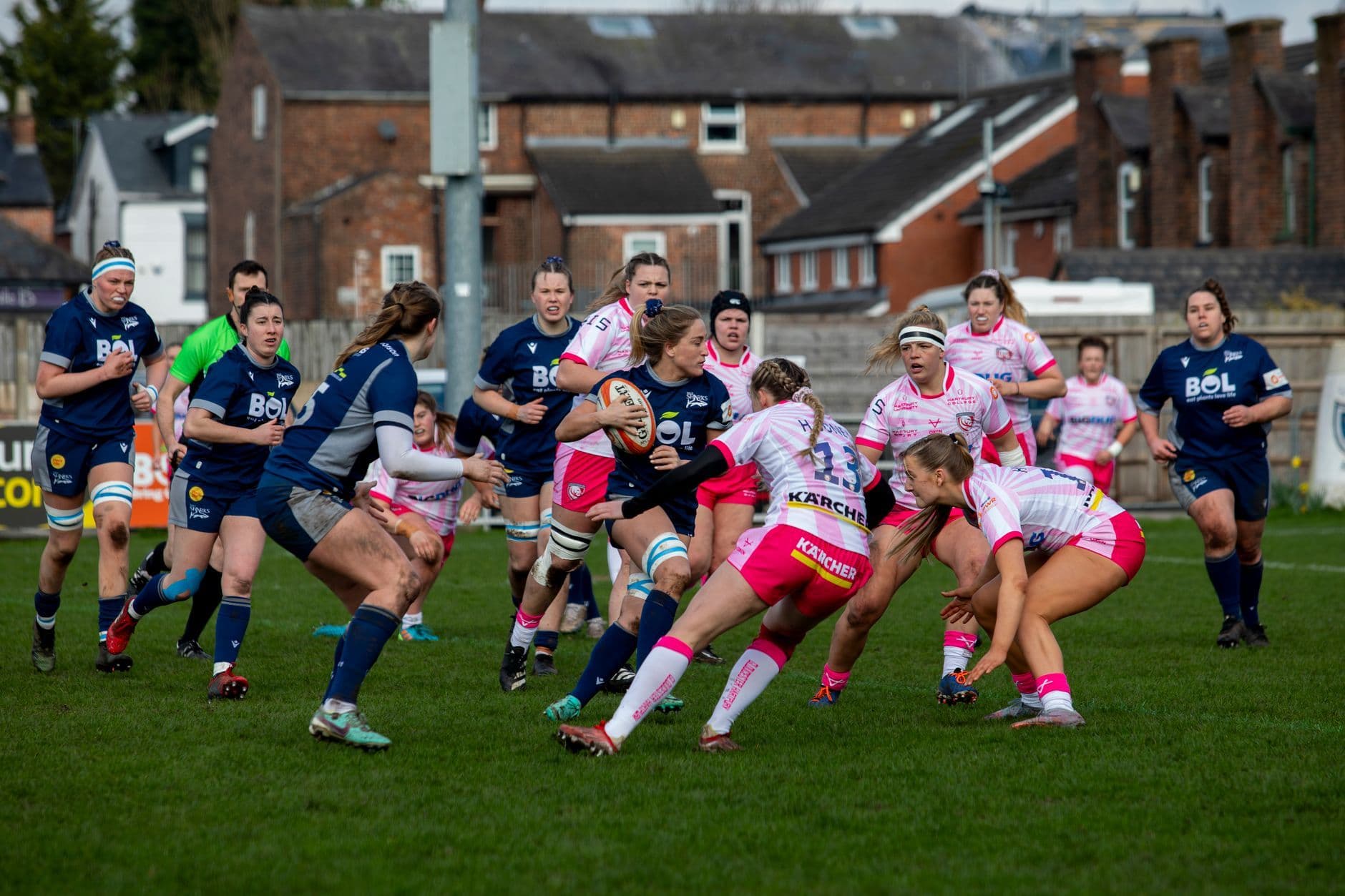 Energetic women's rugby match showcasing teamwork and sportsmanship on a grass field.