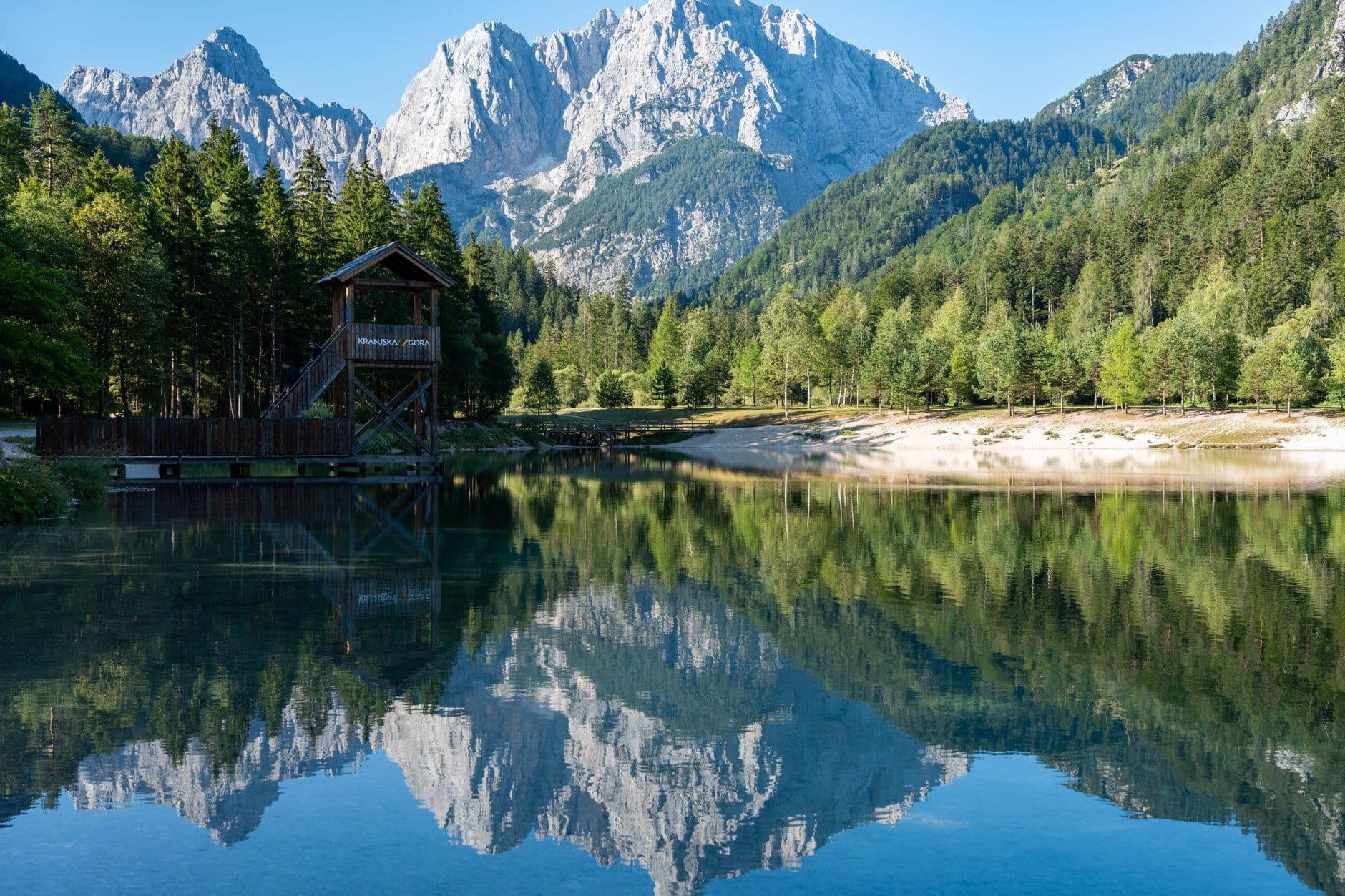 Idyllic lake reflecting majestic Alpine mountains on a sunny summer day.