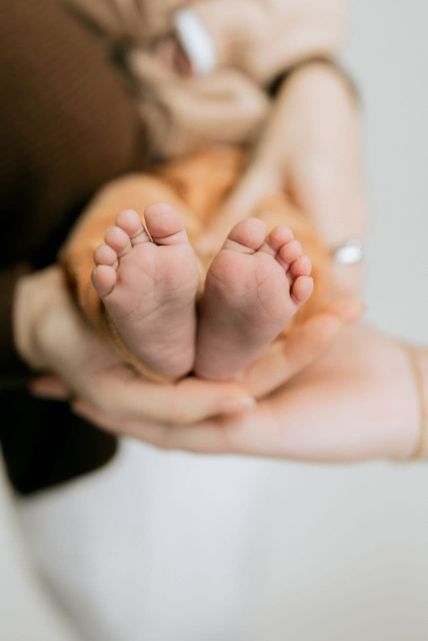Tender close-up of baby's feet held by adult hands, conveying warmth and care.